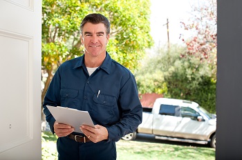 man standing in doorway smiling at camera holding a clipboard
