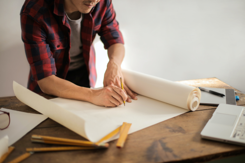 a person sitting at a table drawing building plans